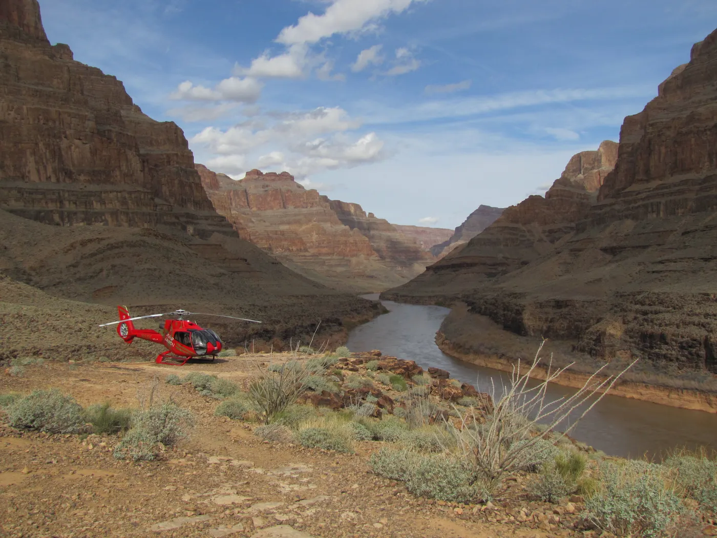 Red tour helicopter landed beside the Colorado River at the bottom of the Grand Canyon